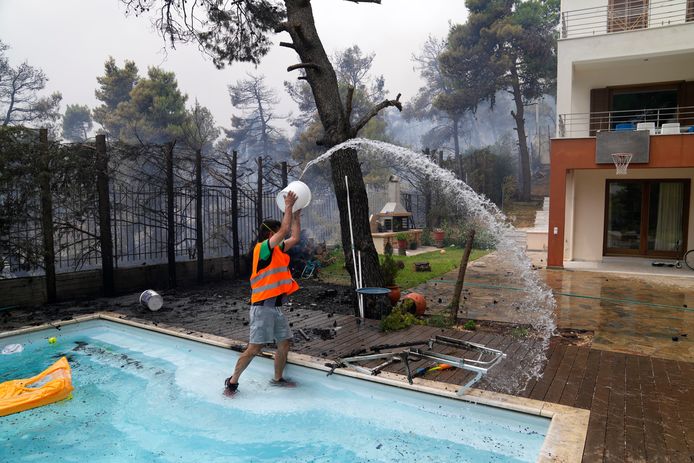 Een man probeert zijn huis te beschermen met water uit het zwembad, 30 kilometer ten noorden van Athene.