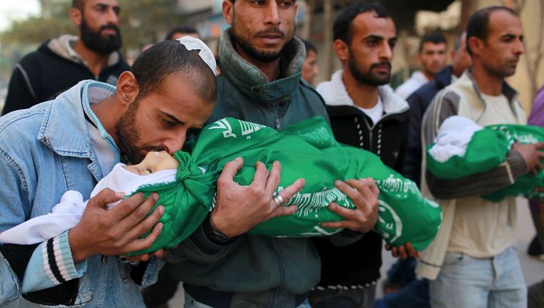 Een vader kust zijn twee kinderen op hun begrafenis zondag. Zijn dochter van 18 maanden en zijn zoon van 3 zijn bij de aanvallen op Gaza om het leven gekomen. Beeld REUTERS