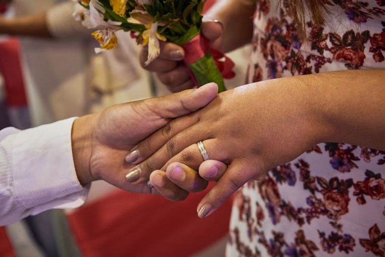 Een pasgetrouwd stel houdt elkaars hand vast bij een plechtigheid ten zuiden van Manilla op de Filipijnen. Beeld Jes Aznar / Getty