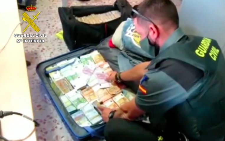 Een politieman toont de valiezen van de Belgische bestuurder, bomvol met bankbiljetten. Beeld Guardia Civil