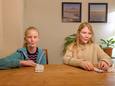 De zusjes Janna (9, blauw vestje) en Ella (11, beige trui) proberen de nieuwe sabbeltest, ofwel de lollypoptest, voor thuis uit.