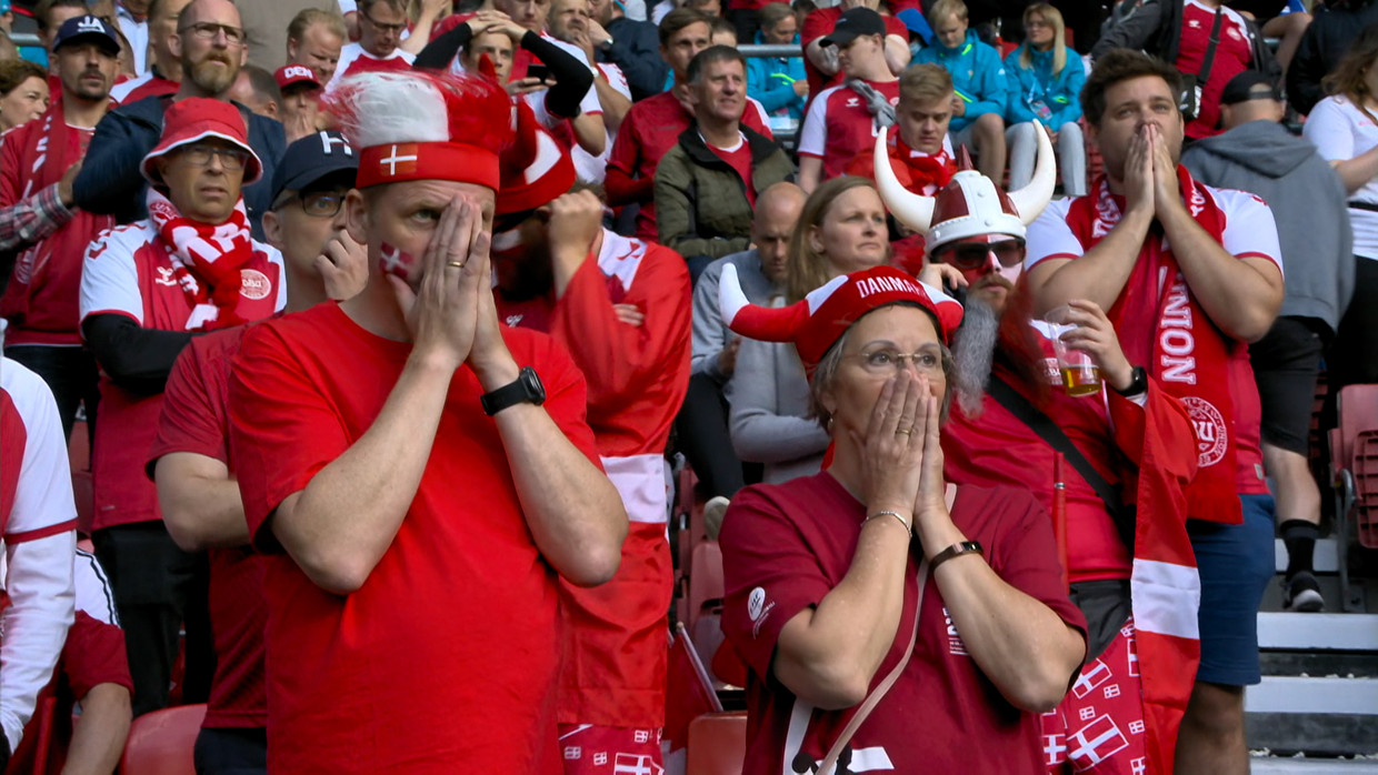 Deense fans reageren geschokt wanneer Christian Eriksen ineens op het veld in elkaar zakt. Beeld VRT