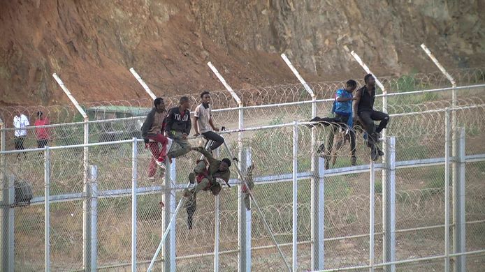Afrikaanse migranten bedwingen het hekwerk aan de grens tussen Marokko en de Spaanse exclave Ceuta in Noord-Afrika.