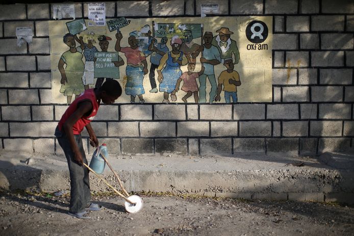 Een jongetje loopt langs een Oxfamposter in Port-au-Prince.