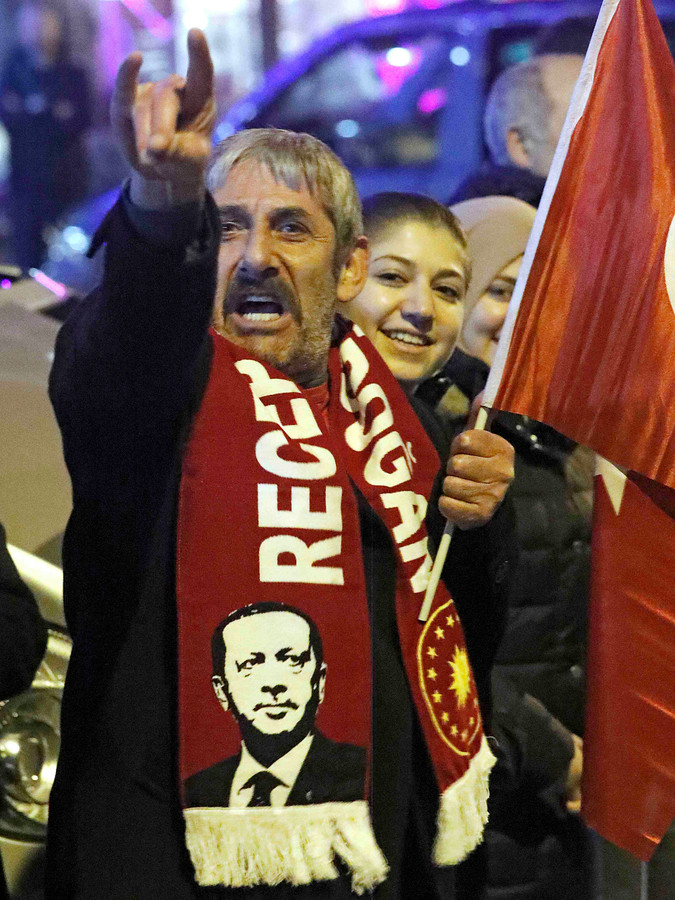 Een Erdogan-aanhanger in Rotterdam maakt het teken van de Grijze Wolven, een Turks extreemrechtse organisatie.