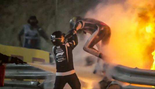 Romain Grosjean verlaat zijn zojuist in tweeën gebroken Formule 1-auto en ontsnapt uit de ontstane vlammenzee.