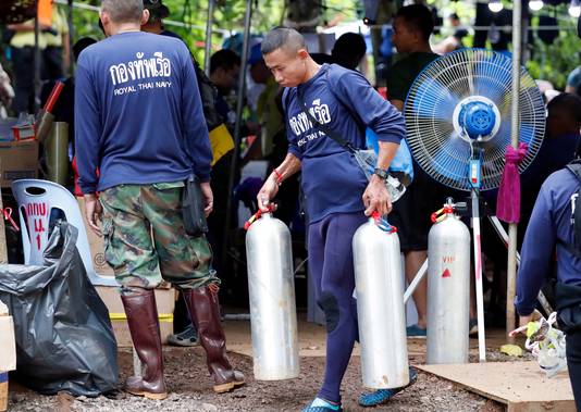 Marinepersoneel dragen zuurstofflessen naar de ingang van het grottencomplex