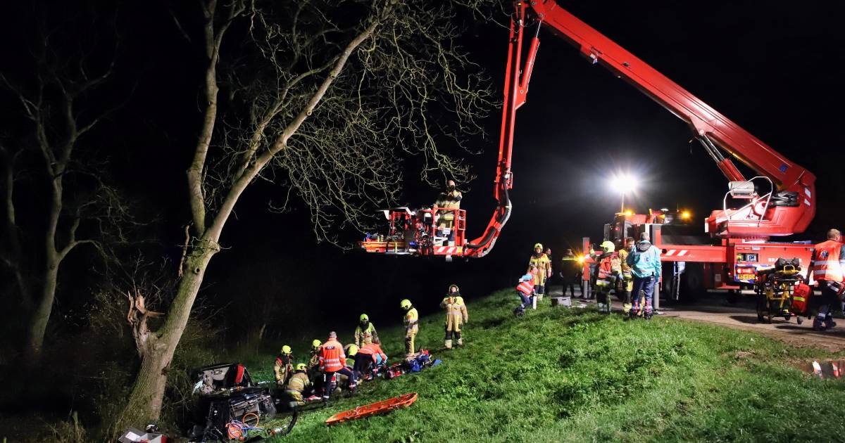 Drie zwaargewonden nadat auto onderaan de dijk tegen boom botst: traumahelikopter landt bij ongeval.