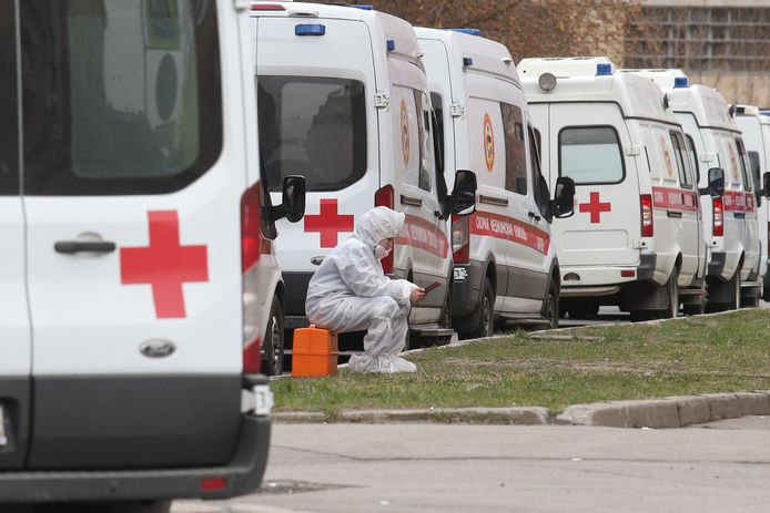 Een Russische gezondheidswerker rust even uit vlak bij enkele ambulances.