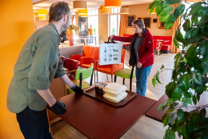 Kok Roy van Wijk zet, met gepaste afstand, de maaltijd voor een klant op tafel.