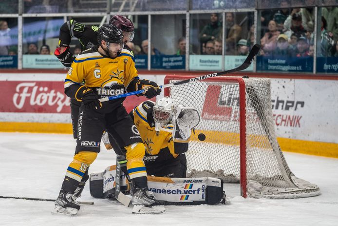 Goalie Cedrick Andree probeert de puck te stoppen met een uiterste krachtsinspanning. Kilian van Gorp houdt de tegenstander tegen.
