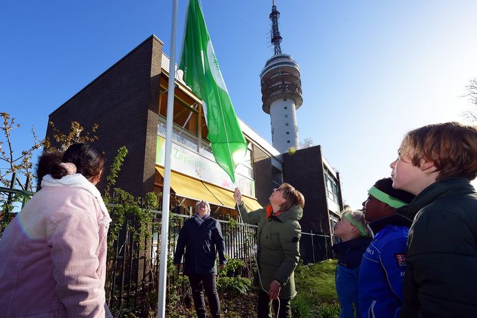 Basisschool Zilverlinde is Eco-school en mag de Groene Vlag hijsen. Wethouder Klaar Koenraad kijkt toe.