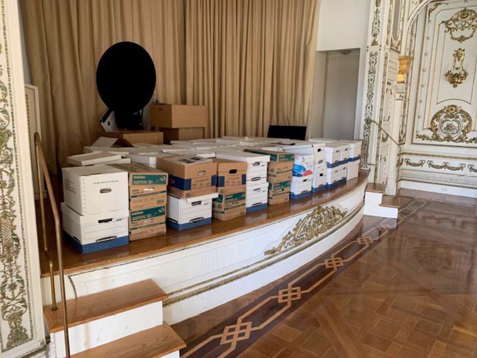 Foto uit de akte van beschuldiging: dozen met documenten opgeslagen op een podium in de White and Gold-balzaal in Mar-a-Lago.