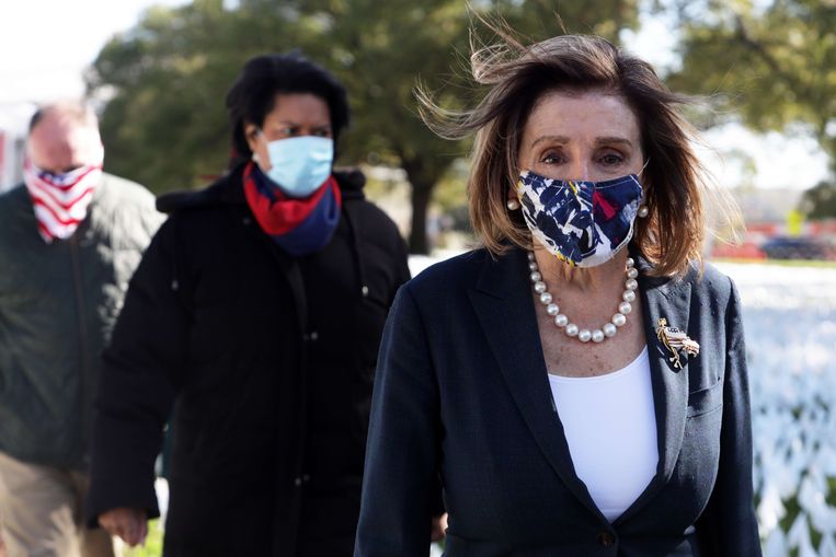 Nancy Pelosi, voorzitter van het Huis van Afgevaardigden, loopt door een kunstwerk met 240.000 witte vlaggetjes. Elk vlaggetje staat voor een Amerikaan die stierf door corona. Beeld AFP