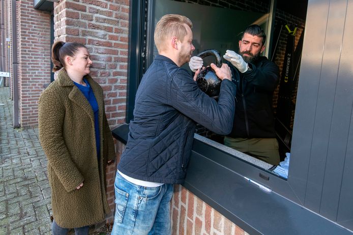 Bram Masselink krijgt bij de achteringang van Het Sportlokaal uit handen van Gerrit Kasteel een kettlebell overhandigd.