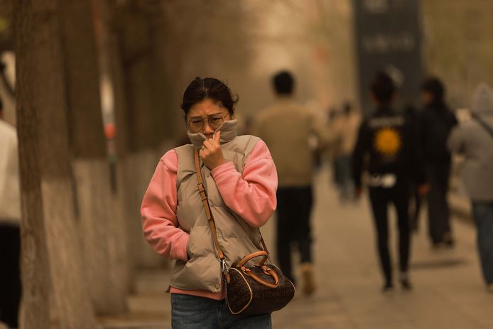 Een vrouw op straat tijdens de zandstorm in Shenyang, in de noordoostelijke Chinese provincie Liaoning.