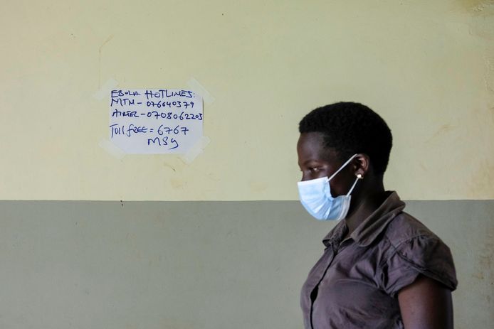 Een vrouw loopt langs een papiertje met telefoonnummers voor ebolapatiënten in Mubende, Oeganda. Beeld van eind vorige maand.