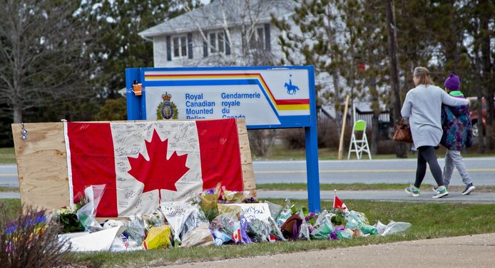 Een vrouw loopt met haar dochter voorbij een plek in het Canadese Portapique waar bloemen zijn neergelegd ter nagedachtenis van de dodelijke slachtoffers.