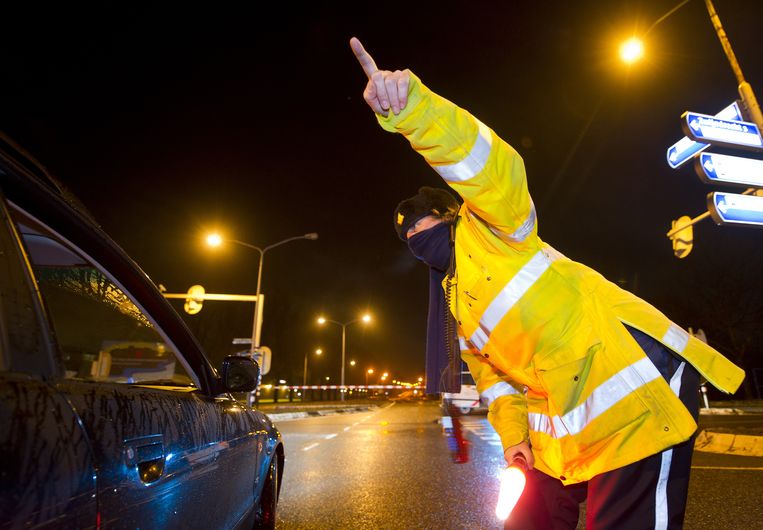 Een politieagent met een sjaal tegen eventuele giftige dampen regelt in januari 2011 het verkeer in Zwijndrecht. Op het nabijgelegen spooremplacement Kijfhoek stond een treinwagon met ethanol in brand. Beeld ANP