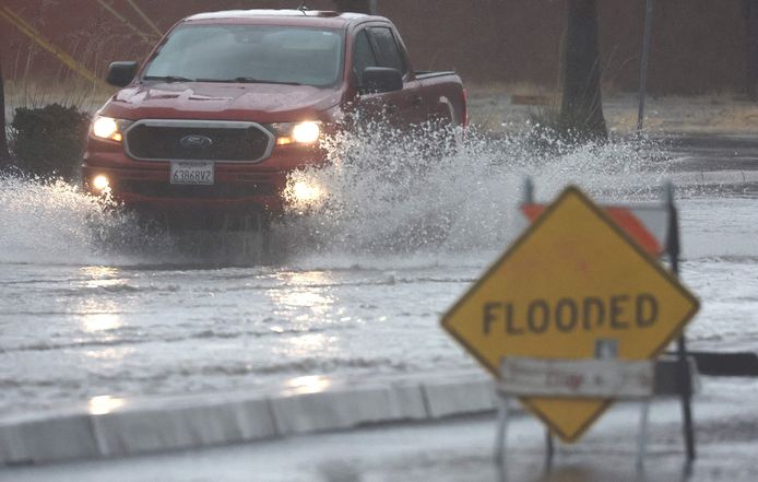 Auto's rijden door een overstroomde straat in Palm Springs, Californië.