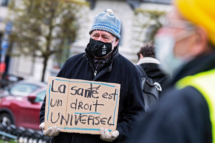 Een man protesteert in Brussel voor het opheffen van de patenten op coronavaccins en -behandelingen. "Gezondheid is een mensenrecht", staat op zijn bordje te lezen.
