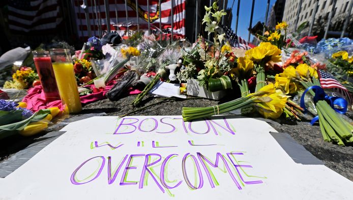 Mensen hebben bloemen neergelegd op de plaats waar de bommen ontploften. Op het papier staat de tekst 'Boston zal overwinnen'.