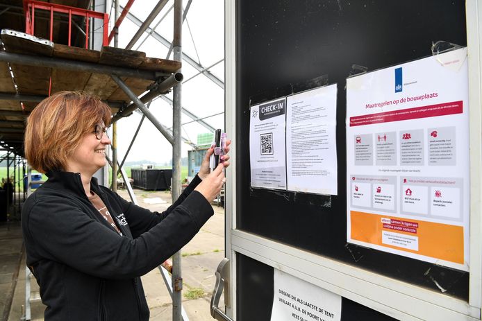 Voorzitter Mariska van Nijnatten scant de QR-code bij de check-in van de bouwtent van haar buurtschap Schijf.