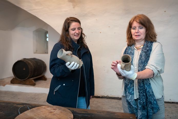Annette Zeelenberg (links) en conservator Marieke Knuijt in de bierkelder met enkele puntgave bierpullen die in de gracht van het kasteel zijn gevonden.
