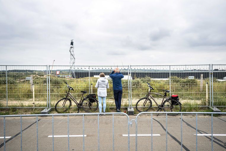 Voorbijgangers proberen een glimp op te vangen van de voorbereidingen van de Formule 1-race op het circuit van Zandvoort. Beeld ANP