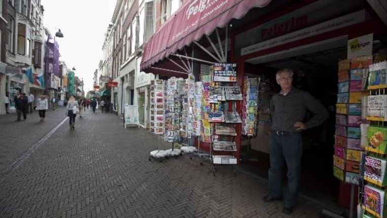 Een winkelier in de Korte Poten in Den Haag kijkt werkeloos toe voor zijn donkere winkel tijdens de stroomstoring (ANP) Beeld 
