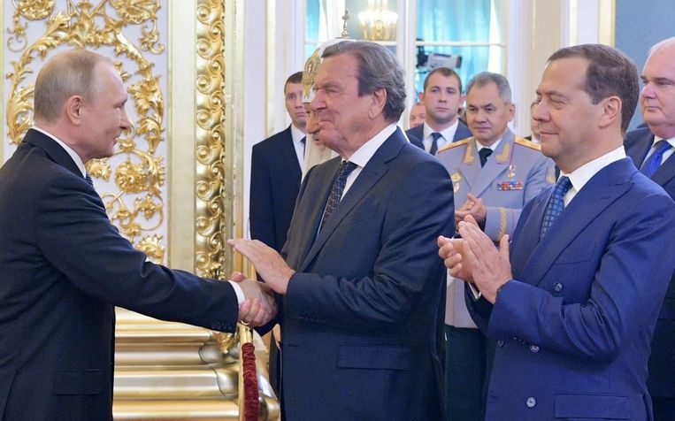Poetin (links) en Schröder schudden elkaar te hand, terwijl Medvedev toekijkt.  Beeld AFP