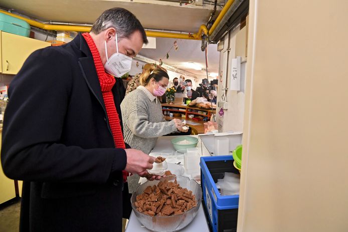 De Croo aan de slag met tiramisu. Achtergrond: Evelyne Huughe van Een Hart Voor Vluchtelingen.