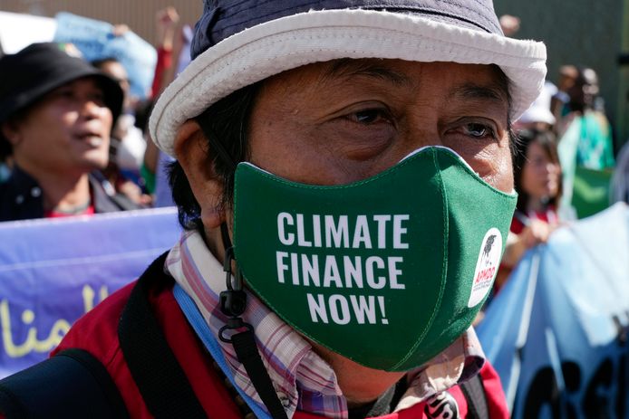 Een activist draagt een masker met het opschrift “klimaatfinanciering nu!” tijdens de top in Sharm el-Sheikh.