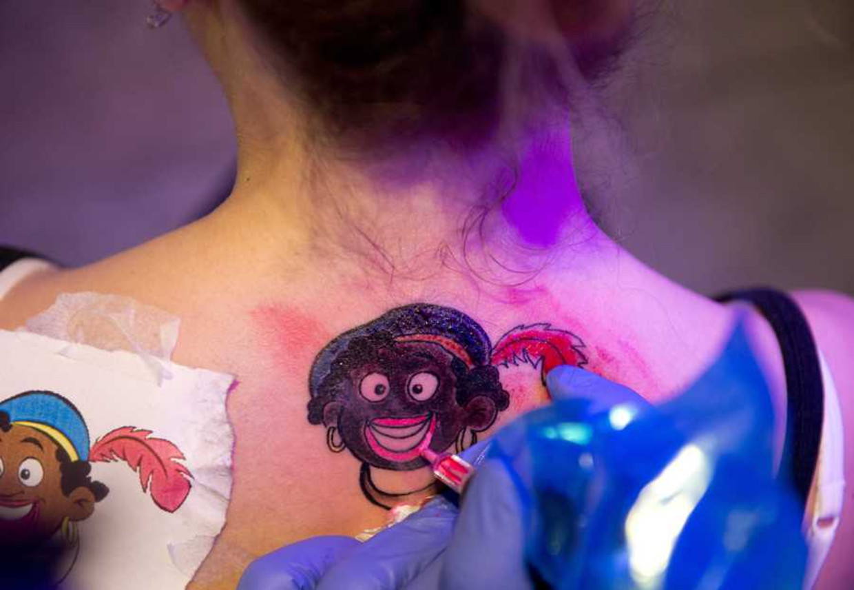 Een vrouw laat een tatoeage van Zwarte Piet zetten. Beeld anp