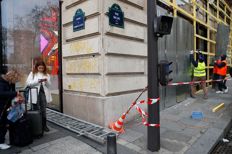CHAMPS-ÉLYSÉES Werklieden timmeren de etalages dicht van een winkel in het centrum van Parijs. Beeld AP