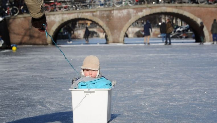 Een baby wordt voortgetrokken in een plastic bak op de Amsterdamse grachten. Beeld anp