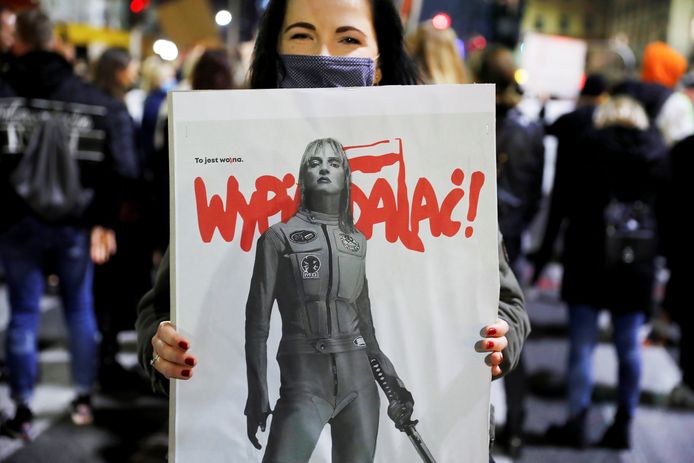 Archiefbeeld: foto van een betoger in Polen met een bord met de belediging ‘wypierdalaj’ (beleefd vertaald als ‘trap het af’ red.)