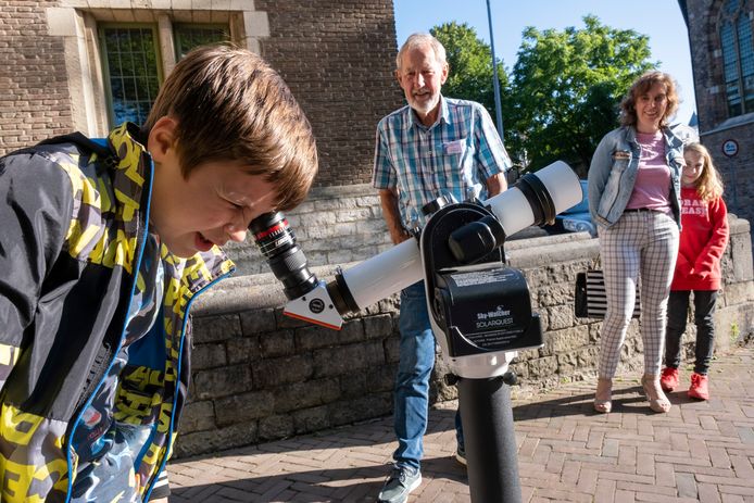 Levani de Groot (9 jaar) kijkt met een telescoop -  voorzien van veilige filters - naar zonnevlekken. Rechts Jan Hellema van de sterrenwacht in Middelburg.