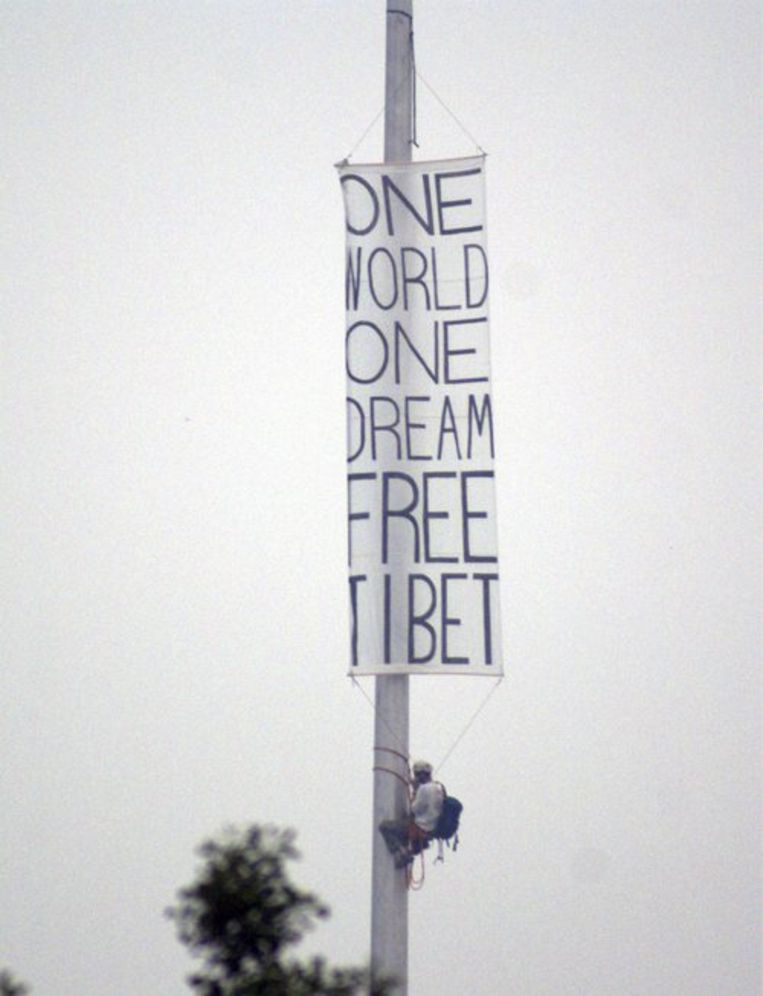 Eenactivist hangt een spandoek op valkbij het Olympisch Stadion in Peking. Foto EPA Beeld 