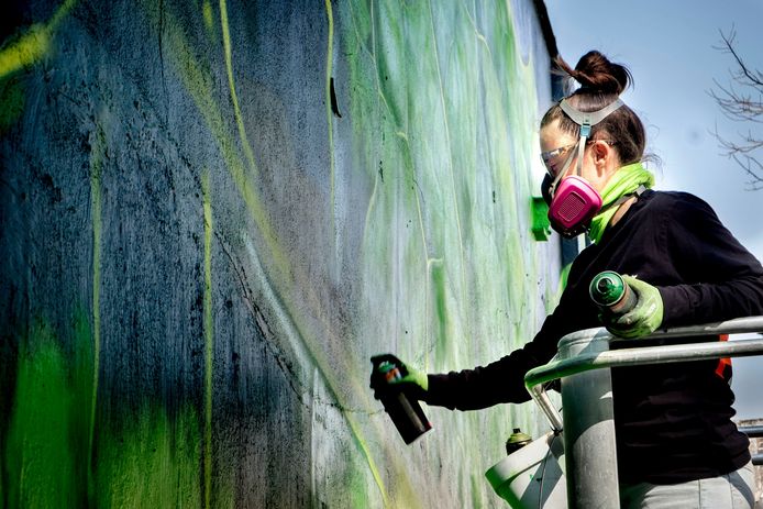 Straatkunstenaar Adele Renault tijdens het maken van de muurschildering.