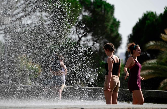Toeristen zoeken tijdens de hittegolf verkoeling in een fontein in Madrid.