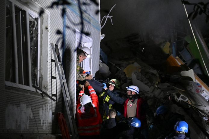 Reddingswerkers dragen een persoon uit het zwaar vernielde flatgebouw.