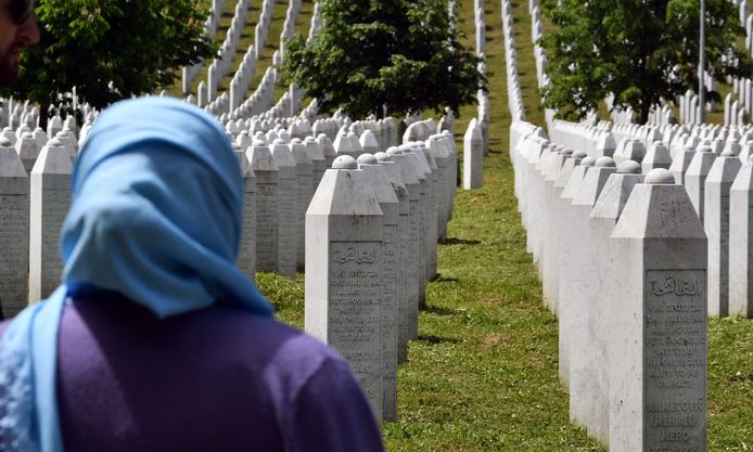 Een vrouw rouwt bij het kerkhof en het herdenkingsmonument voor de slachtpartij van Srebrenica.