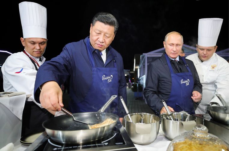De Chinese president Xi Jinping bakt een pannekoekje tijdens een bezoek aan het Eastern Economic Forum in Vladivostok. Zijn Russische collega Vladimir Poetin kijkt toe. Beeld AP