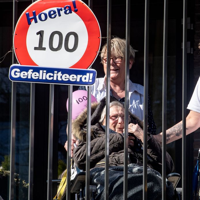 Mevrouw Mali-Geijsberts geniet vanaf haar balkon van de aubade. Ze is vandaag 100 jaar geworden, maar mag in het verpleeghuis geen bezoek ontvangen.
