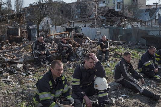Brandweermannen nemen pauze tijdens de reddingswerken aan de gebombardeerde wooncomplexen in Borodjanka.