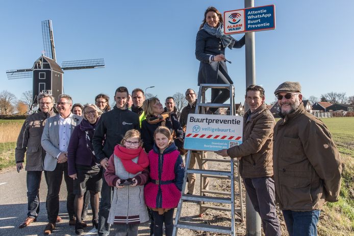 Burgemeester José van Egmond monteert onder het toeziend oog van bewoners het bord dat er op wijst dat in Waarde buurtpreventie geldt.