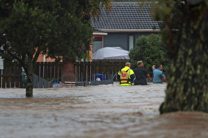 Noodwerkers en een man waden door de overstroomde straten van Auckland, Nieuw-Zeeland, op vrijdag 27 januari.