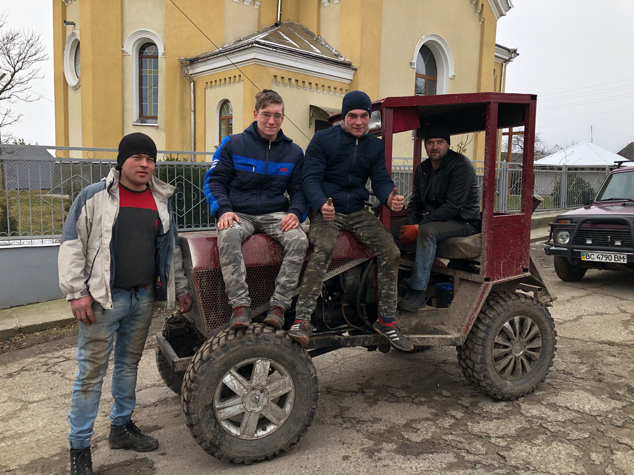 ‘Traktorist’ Volodja Volosjin achter het stuur van zijn zelfgebouwde trekker, in gezelschap van enkele dorpsgenoten. Beeld Michiel Driebergen
