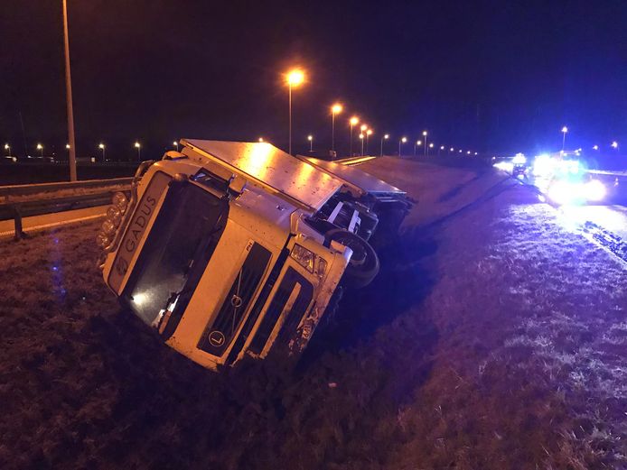 De truck ligt in de gracht tussen de oprit van de E40 en de snelweg zelf.